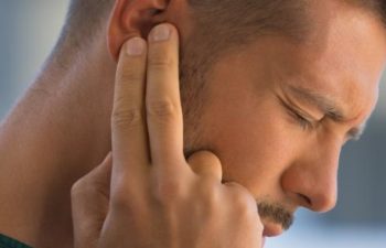 Young man suffering from ear pain. Ear infection.