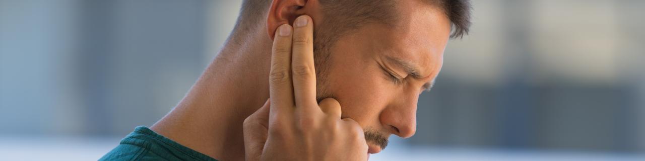 Young man suffering from ear pain. Ear infection.